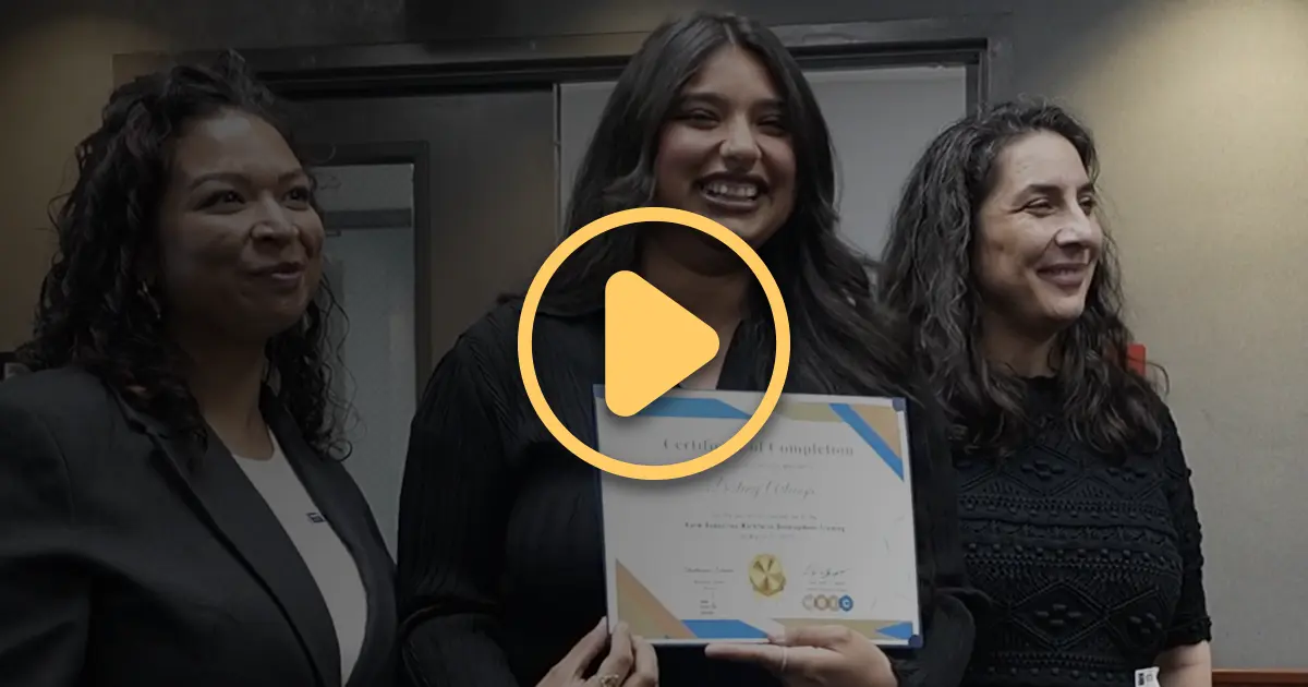 Una graduada del Programa del Centro de Educación y Recursos para Trabajadores sonríe al recibir su certificado.